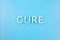 The word cure laid with thick aluminium letters on blue background