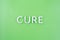 The word cure laid with thick aluminium letters on green background