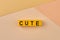 Word cute written on yellow blocks against color background.