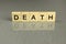 Word death, made of square wooden letters on a gray background