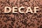 Word Decaf made of wooden letters on brown background with coffee beans