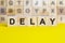 word delay is written on wooden cubes on a bright yellow surface, concept