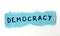 The word Democracy on blue paper