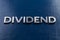 The word dividend lait by silver metal letters on classic blue color painted background with selective focus