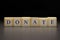 The word DONATE written on wooden cubes isolated on a black background
