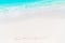 Word Dream handwritten on sandy beach with turquoise water