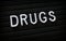 The word Drugs on a Letter Board