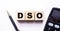 The word DSO Days Sales Outstanding is written on wooden cubes between a pen and a calculator on a light background