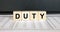 Word Duty made with wood toy blocks on financial tables