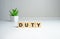 the word duty wooden cubes, duties of people, gray background top view