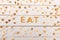 Word eat from breakfast cereal letters and alphabet corn flakes on wooden table