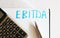 The word EBITDA is written by hand on the paper