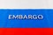 the word embargo laid with silver metal letters on russian tricolor flag