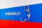 the word embargo laid with silver metal letters on russian tricolor flag with silver handcuffs