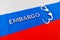 the word embargo laid with silver metal letters on russian tricolor flag with silver handcuffs