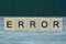 Word error from wooden letters on a gray table