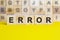 Word error is written on wooden cubes on a bright yellow surface, concept