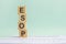 word ESOP with wood building blocks, light gray background. document with numbers on background, business concept. space