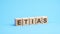 word etias made with wood building blocks. text is written in black letters and is reflected in the mirror surface of