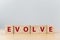 The word EVOLVE on wooden cube block on wood table