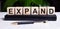 The word EXPAND is written on the wooden cubes of the diary near the handle