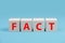 The word fact is standing in red letters on wooden cubes