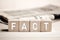 The word fact on wooden blocks against a newspaper background. Reliable, honest and accurate news making in media concept