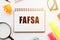 The word Fafsa in a notebook on white table with office tools. Business concept