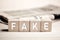 The word fake on wooden blocks against a newspaper background. Fake news in media concept