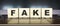 Word FAKE. Wooden cubes with letters isolated on a laptop keyboard. Business Concept