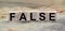 The word FALSE is written on wooden cubes. Wooden cubes in the open air, overlooking the countryside. For business related design