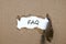 The word faq appearing behind torn paper