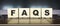 Word FAQS. Wooden cubes with letters isolated on a laptop keyboard. Business Concept