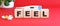 The word FEEL is made of wooden cubes on a red background. Medical concept.