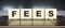 Word FEES. Wooden cubes with letters isolated on a laptop keyboard. Business Concept