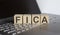 Word FICA made with letters on wooden blocks on the laptop