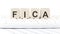 Word FICA made with letters on the wooden blocks on the laptop