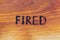 The word fired handwritten with hand woodburner on flat brown wood surface