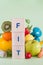 Word FIT made with wooden blocks. Fruits, vegetables, measuring tape and dumbbells, healthy food and lifestyle concept