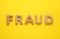 Word Fraud made of wooden letters on yellow background, flat lay