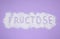 Word Fructose made of powder on violet background