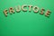 Word Fructose made of wooden letters on green background, flat lay. Space for text