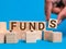 Word funds on wooden cubes against blue background. Funding and business concept.