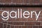The word `gallery` written in neat paint, on a wall.