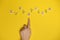 Word gender depicted by using wooden blocks and flowers on yellow bee background with woman hand pointing on it