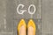 Word go written on gray sidewalk with women legs, top view