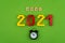 The word goal 2021 is lined with wooden letters on a green background. Small black alarm clock. Figures from the