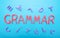 The word grammar on a blue background and letters scattered in a chaotic manner, the concept of literacy at school, inscription