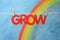 The word grow with a blue sky and colorful rainbow.