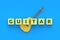 Word guitar on cubes near acoustic instrument on blue background